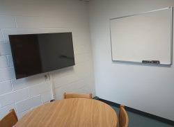 Table and chairs with monitor and whiteboard